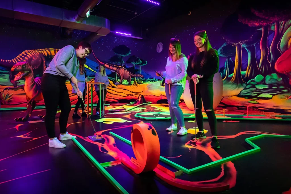 Besucher spielen Schwarzlicht Minigolf mit Hindernissen