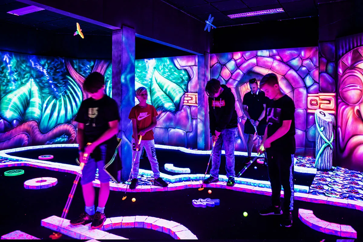 Gruppe Jugendlicher spielt Schwarzlicht Minigolf GolfZone
