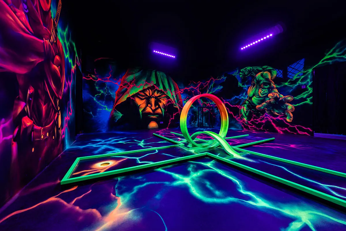 Minigolfbahn mit Superhelden Motiv an der Wand