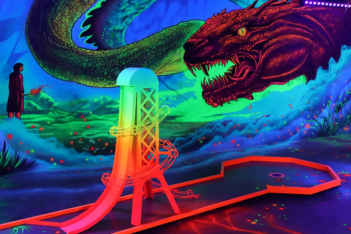 Eine leuchtende Minigolfbahn mit einem Spiralhindernis vor Drachen Szene