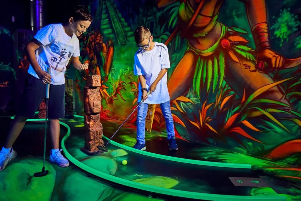 zwei freunde spielen dschungel bahn beim Schwarzlicht Minigolf