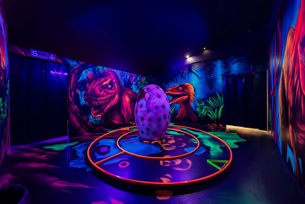 Eine bunte Minigolfbahn mit einem begehbaren Dino Ei in der Mitte.